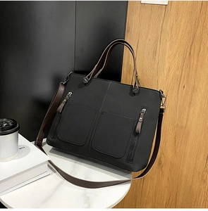 Detail of black matte tote bag with dual zipper pockets and brown contrast shoulder straps