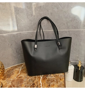Détail du sac cabas en cuir noir mat avec logo FASHION et boucles en métal sombre