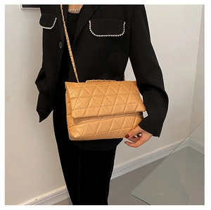 Détail du motif matelassé triangulaire sur sac bandoulière beige avec chaîne dorée