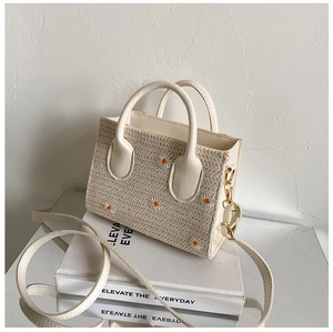 Détail du sac en paille avec broderie marguerite et boucles en métal doré sur le côté