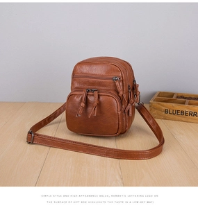 Detail view of brown textured leather mini bag with multiple zipper compartments