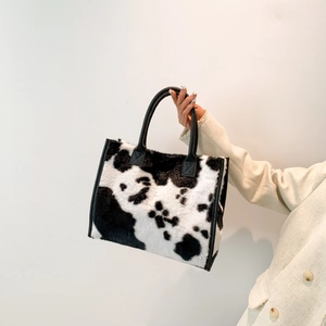 Detail van de zachte faux fur shopper met koeprint en zwarte imitatielederen grepen