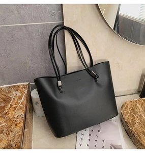 Détail d'un sac cabas en cuir noir avec inscription FASHION et boucles métalliques