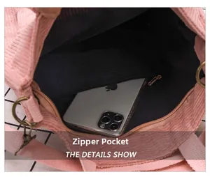Detail view of pink corduroy bag interior featuring a black lining and zip pocket