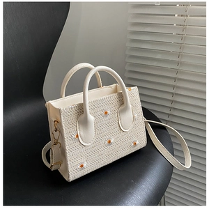 Détail du sac cabas en paille avec broderie marguerite et boucles dorées élégantes
