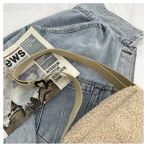 Détail d'un sac bandoulière en polaire beige avec sangle réglable sur fond en jean