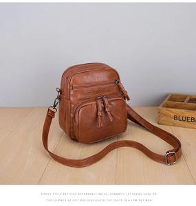 Detail view of vintage brown multi-pocket crossbody bag with metallic zipper hardware