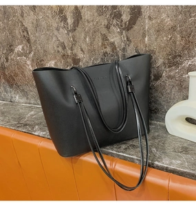 Détail du logo FASHION embossé sur un sac cabas noir en similicuir avec longues anses