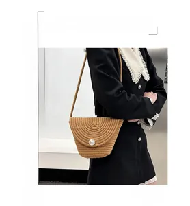 Detailed close-up of handmade straw bucket bag featuring a large pearl embellishment