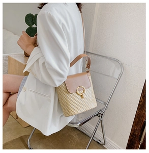 Fashionable straw bucket bag with brown leather flap worn by model in casual chic style