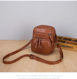 Detail view of brown multi-pocket crossbody bag with soft pebbled leather texture