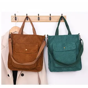 Detail of corduroy tote bags with metal buckles hanging on a wooden rack