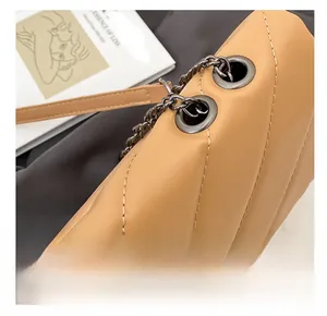 Detail of chain strap and metal eyelets on a camel quilted leather crossbody bag