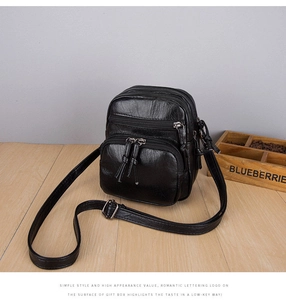 Macro view of multi-compartment black crossbody bag with pleated texture and fringe zippers