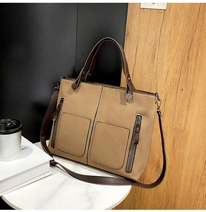 Detail of khaki matte leather tote bag with brown handles and decorative zippers