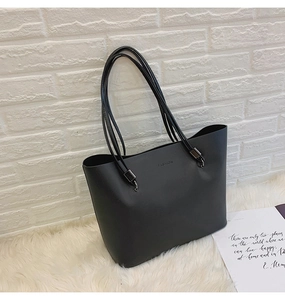 Vue détaillée d'un grand sac cabas noir texturé avec l'inscription 'FASHION' et de fines anses