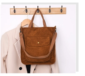 Detail view of dark brown corduroy crossbody bag with front pocket and metal fastener