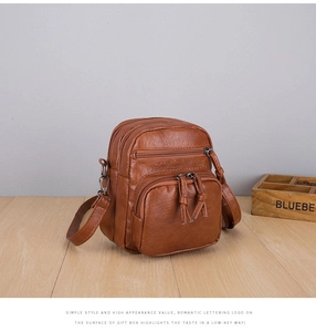 Detail of brown PU leather crossbody bag featuring multiple zipper pockets and texture