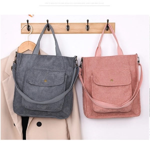 Detail of corduroy tote bags with metal buckles and front flap pockets on wooden hooks