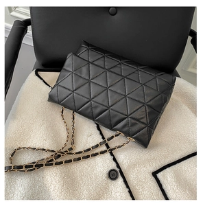 Détail du sac matelassé noir classique avec motifs géométriques et bandoulière en chaîne dorée