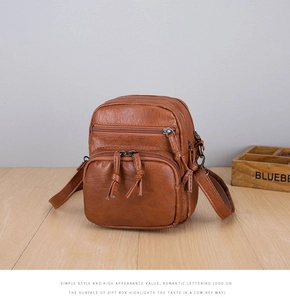 Detail of caramel brown pebble leather bag with functional multi-zipper compartments