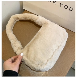 Détail de la texture d'un sac à main en peluche crème avec poignée douce et rabat