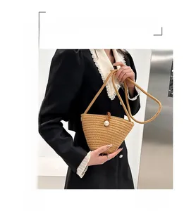 Détail du sac seau en paille avec fermoir perle et cordon de serrage en cuir brun