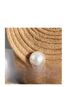 Macro detail of hand-woven straw texture featuring a large white pearl bead accent