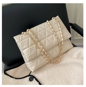 Détail macro du sac à rabat matelassé crème avec bandoulière chaîne dorée sur cuir noir