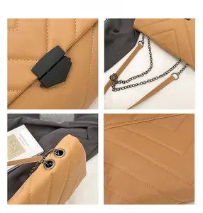 Detail view of brown quilted crossbody bag with matte black clasp and chain strap
