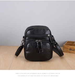 Detail of black pebbled leather crossbody bag featuring multiple zipper pockets and knotted pulls