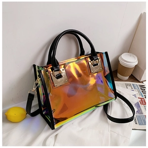Close-up of holographic transparent tote bag with black leather handles and gold hardware