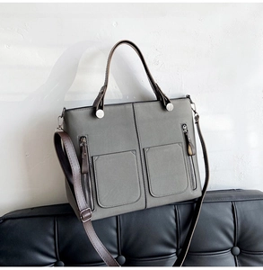 Detail of grey frosted leather tote bag with dual front pockets and silver zippers