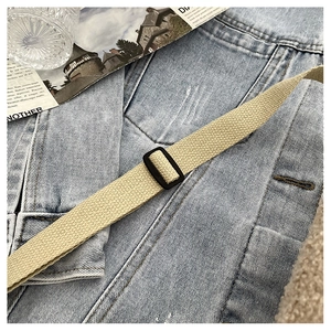 Détail de la bandoulière en toile ajustable avec boucle noire sur un sac beige chic