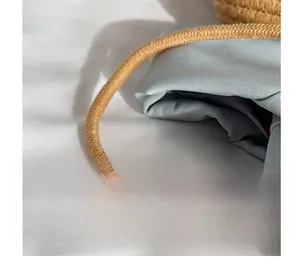Close-up of thick khaki braided rope strap on a light blue fabric bucket bag