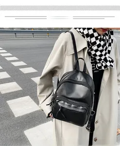 Outdoor shot of a black faux leather backpack with silver zippers and large capacity