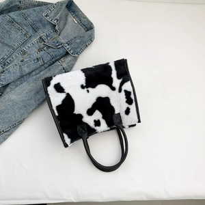 Detail van koeprint imitatiebont draagtas met zwarte lederen hengsels en trendy denim accent