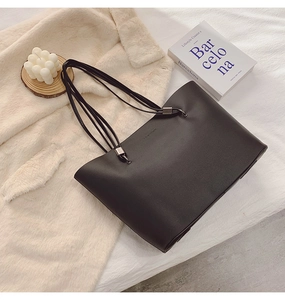 Détail du cabas en cuir noir avec embossage FASHION sur fond en peluche crème doux