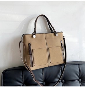 Detail showing khaki nubuck crossbody bag with front pockets on a black sofa