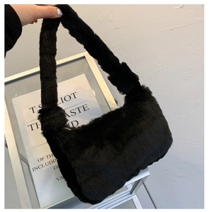 Détail de la texture d'un sac à main en fausse fourrure noire avec anse douce