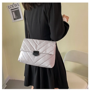 Detail of silver quilted crossbody bag with chain strap and V-pattern stitching