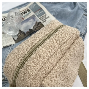 Détail de la texture laine d'agneau beige et du zip argenté d'un petit sac à bandoulière