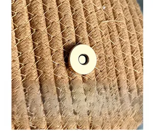 Detail of golden magnetic clasp on handcrafted brown woven straw bucket shoulder bag
