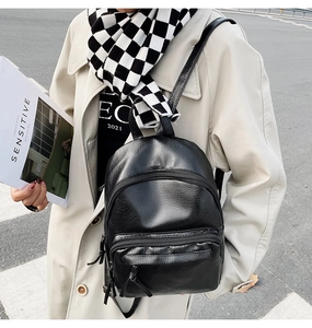 Close-up of black litchi pattern leather backpack with side zippers and front pocket