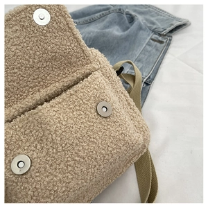 Gros plan d'un sac bandoulière beige en fausse fourrure avec doubles fermoirs aimantés