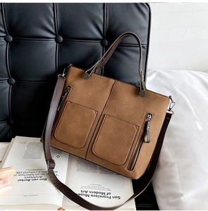 Close-up of a dark brown suede tote bag with double front pockets and bronze metal zippers