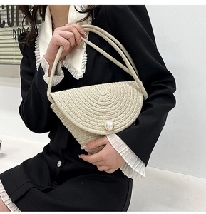 Detailed view of handmade straw bucket bag featuring a large pearl clasp closure