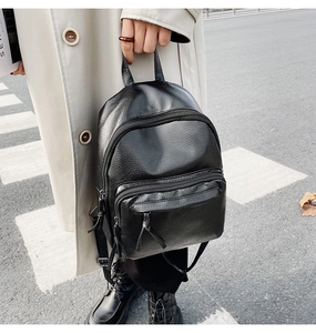 Outdoor shot of a black textured PU leather mini backpack with stylish long leather tassels