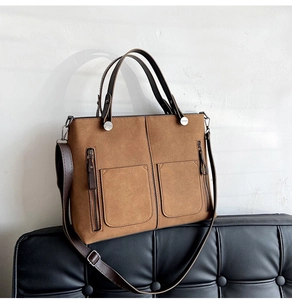Detail of vintage brown suede tote bag with double front pockets and silver hardware accents