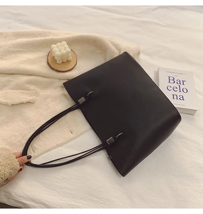 Gros plan du sac cabas noir en similicuir avec boucles argentées sur fond blanc doux